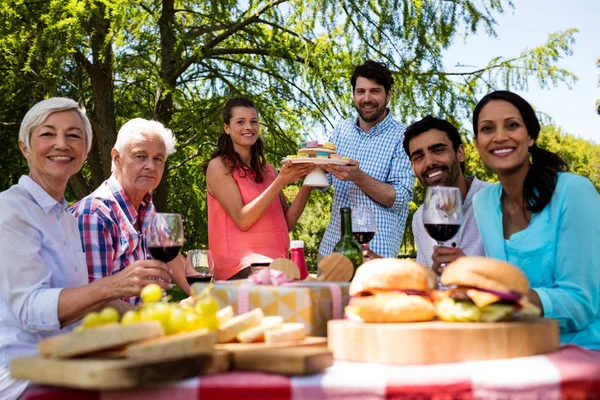 Portrét šťastná rodina s koláčky a červené víno v parku — Stock fotografie