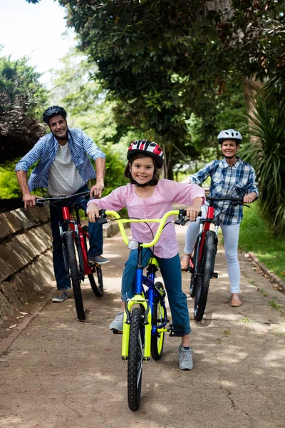Retrato de padres felices e hija de pie con bicicleta en el parque — Foto de Stock