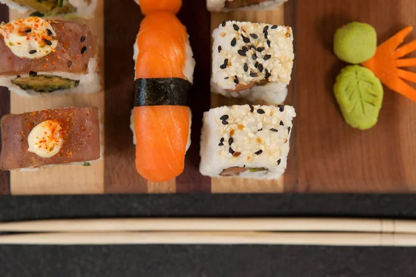 Ensemble de sushis assortis servi avec des baguettes sur une planche en bois — Photo