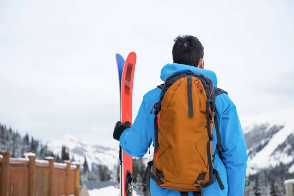Скіпер стоїть з лижами на засніжених горах — стокове фото