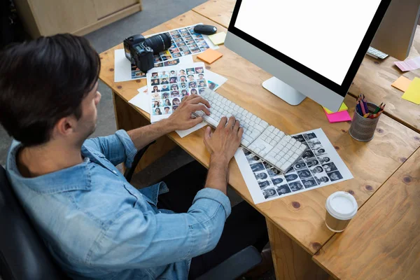 Uomo con fotografie che lavorano su PC desktop — Foto Stock