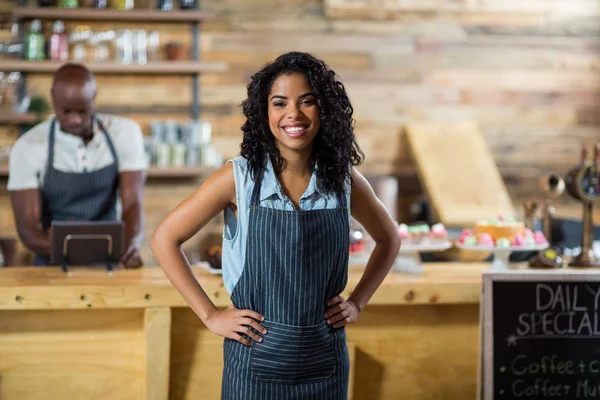 Portrait of smiling waitress standing with hands on hip — Stock Photo, Image