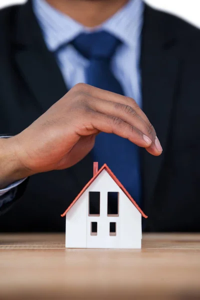 Businessman protecting house model with hands — Stock Photo, Image