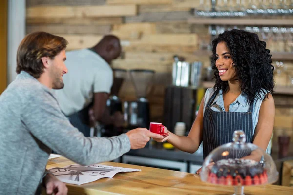 Waitress serving a cup of coffee at counter — Stock Photo, Image