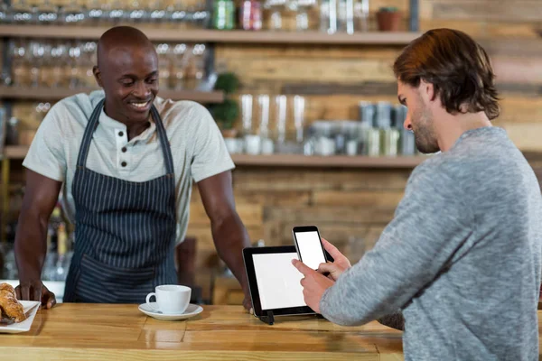 Homme utilisant un téléphone portable au comptoir — Photo