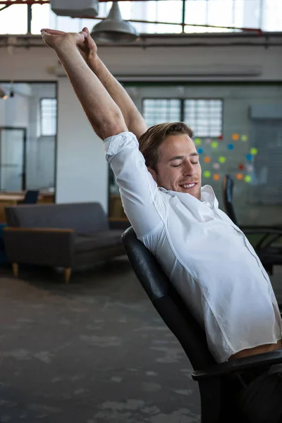 Businessman stretching at desk — Stock Photo, Image