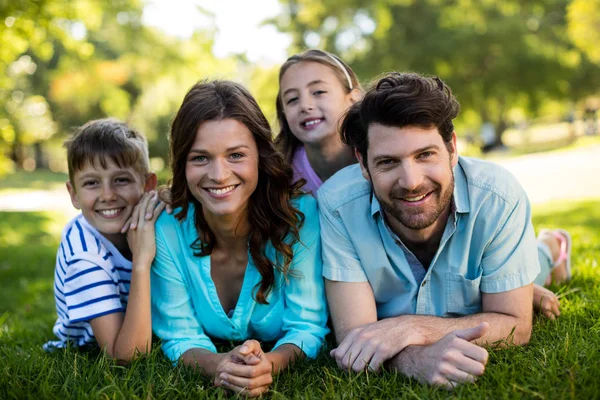 Portrait of happy family lying on grass in park — Stock Photo, Image