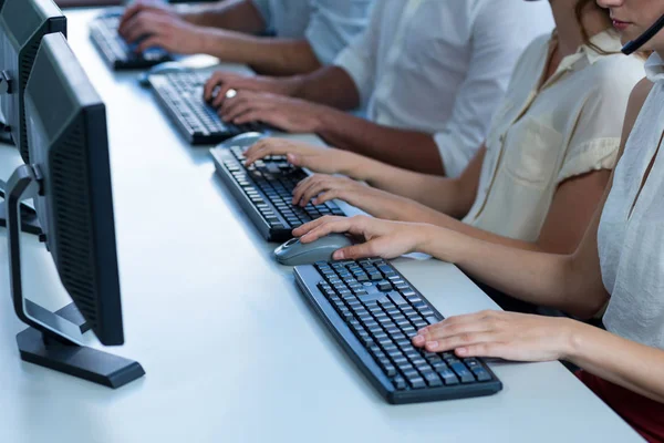 Business executives with headsets using computer — Stock Photo, Image