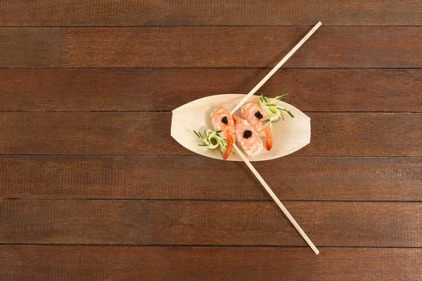 Tre nigiri sushi serveras med ätpinnar i trä båt plattan — Stockfoto