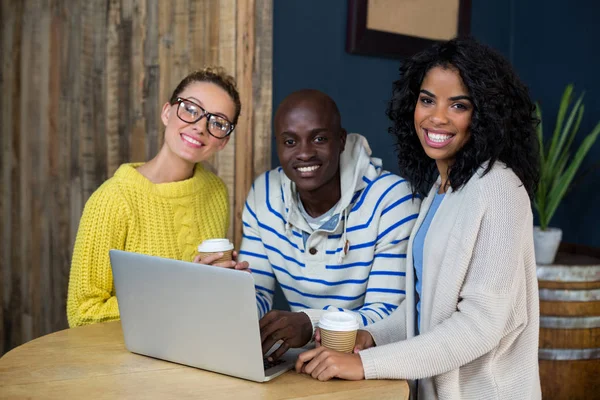 Happy friends using laptop while having coffee in cafe — Stock Photo, Image