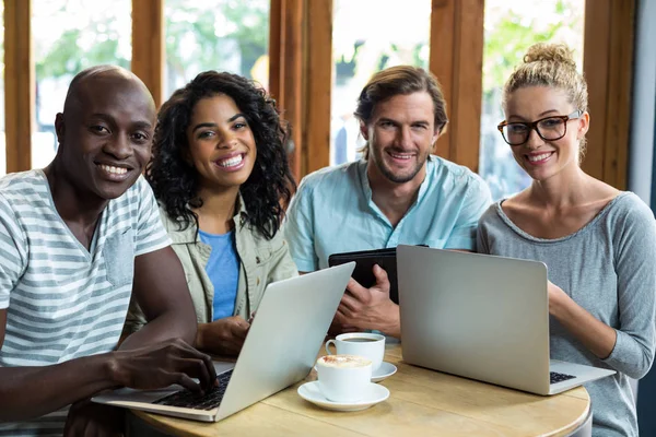 Amigos usando laptop e tablet digital ao tomar café no café — Fotografia de Stock