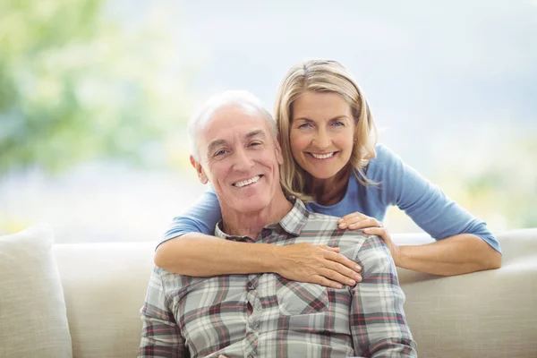 Porträt einer Seniorin, die einen Mann im Wohnzimmer umarmt — Stockfoto