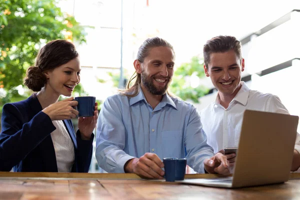 Grupo de amigos que usan el ordenador portátil mientras toman café — Foto de Stock