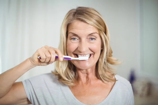 Retrato de la mujer mayor cepillándose los dientes en el baño — Foto de Stock