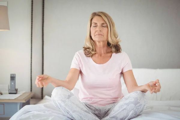 Senior pratiquant le yoga sur le lit — Photo