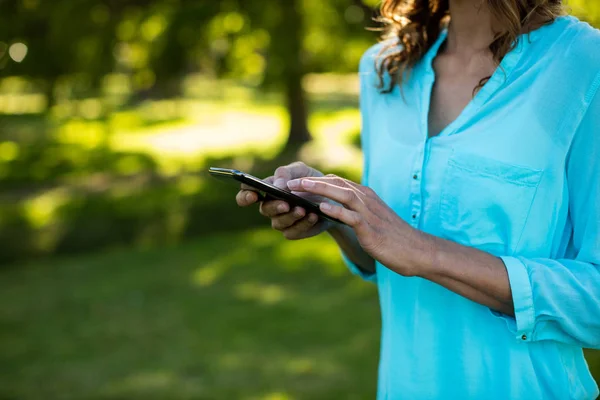 Frau benutzt Handy im Park — Stockfoto
