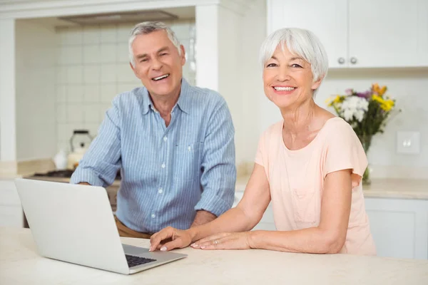 Ritratto di coppia anziana che usa il computer portatile in cucina — Foto Stock