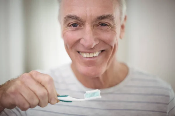 Retrato de homem sênior escovando os dentes no banheiro — Fotografia de Stock