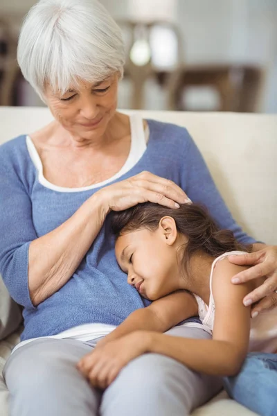 Kleindochter slapen op grootmoeders schoot in woonkamer — Stockfoto