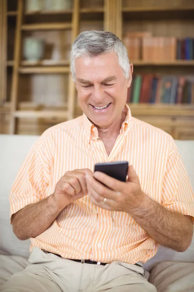 Senior man gebruik mobiele telefoon in woonkamer — Stockfoto