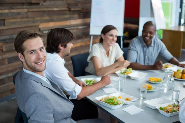 Lächelnde Führungskräfte beim Essen im Büro — Stockfoto