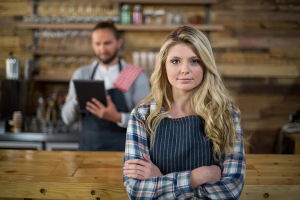 Portrait of waitress standing with arms crossed at counter — Stock Photo, Image