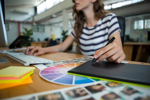 Mid sectie van vrouwelijke grafisch ontwerper, grafisch tablet gebruiken aan balie — Stockfoto