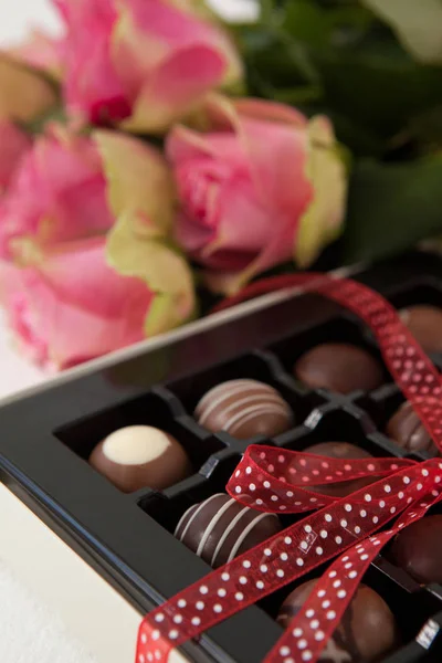 Ramo de rosas y caja de chocolate surtido — Foto de Stock