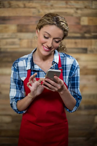 Smiling waitress using mobile phone — Stock Photo, Image