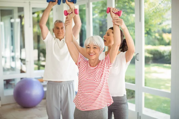 Female trainer assisting senior couple in performing exercise — Stock Photo, Image