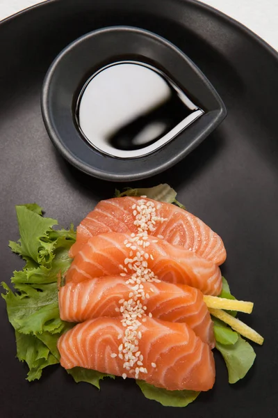 Four sashimi sushi served with soy sauce in black plate — Stock Photo, Image