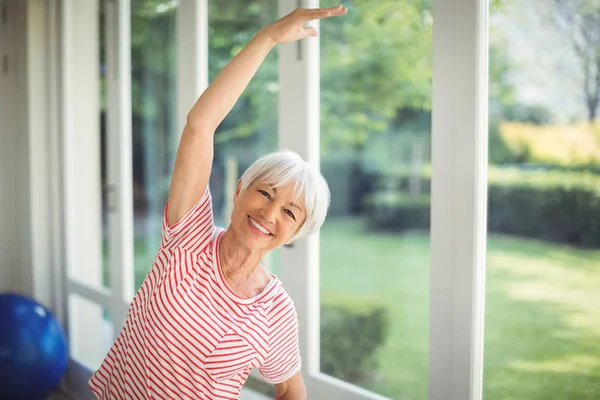 Retrato de mulher idosa realizando exercício de alongamento em casa — Fotografia de Stock