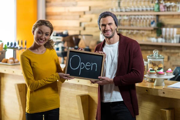 Lächelnde Besitzer stehen mit offener Hinweistafel im Café — Stockfoto