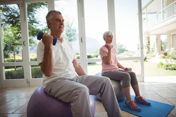 Senior couple exercising with dumbbells on exercise ball — Stock Photo, Image
