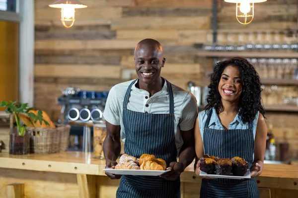 Portrait de serveur et serveuse tenant une assiette de cupcake et croissant — Photo