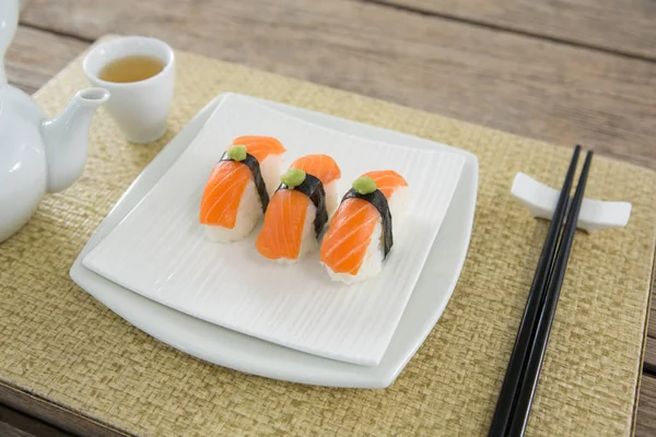 Platta av sushi och te potten höll på matta — Stockfoto