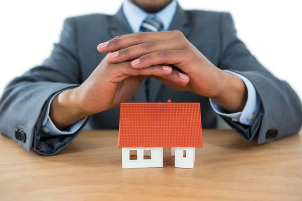 Businessman protecting house model with hands — Stock Photo, Image