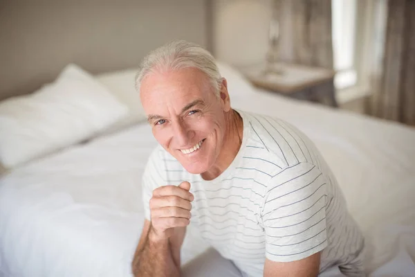 Retrato de homem idoso feliz sentado na cama no quarto — Fotografia de Stock