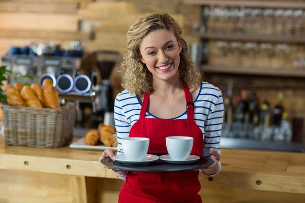 Portret van lachende serveerster permanent met kopje koffie — Stockfoto