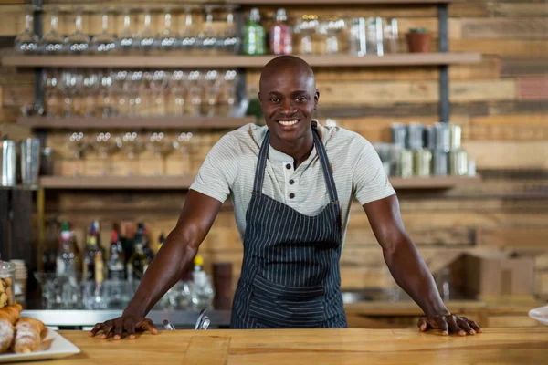 Retrato del camarero sonriente de pie en el mostrador — Foto de Stock