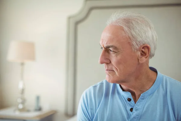 Thoughtful senior man sitting in bed room — Stock Photo, Image