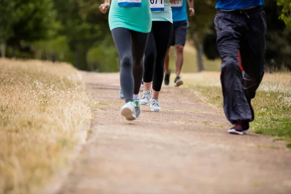 Sección baja de atletas corriendo carrera en el parque —  Fotos de Stock