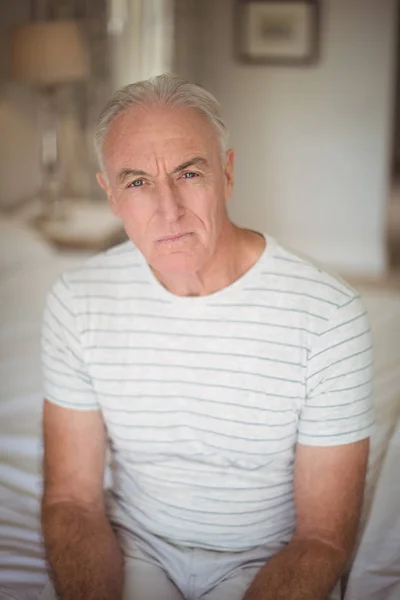 Retrato de homem idoso sentado na cama no quarto — Fotografia de Stock