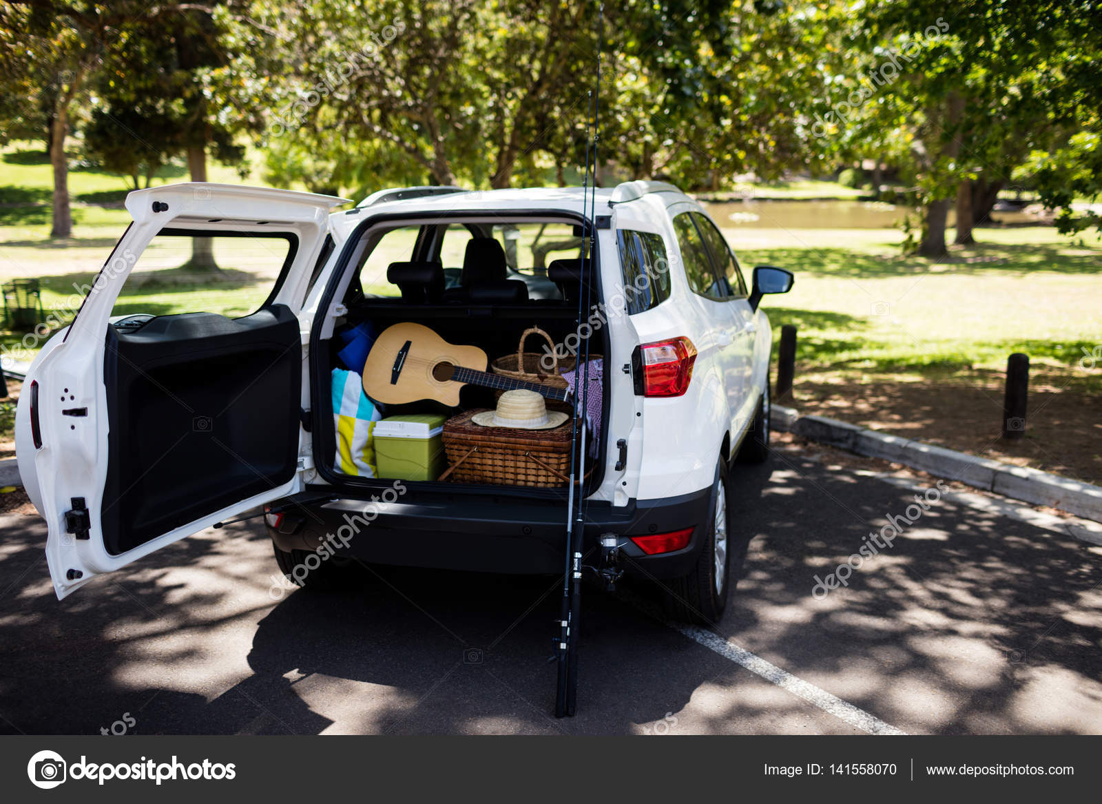 Guitar, fishing rod, picnic basket in car trunk — Stock Photo