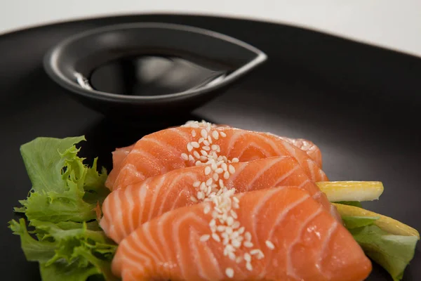 Cuatro sushi sashimi servidos con salsa de soja en plato negro — Foto de Stock