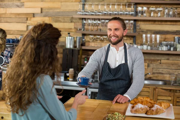 Kellner serviert dem Kunden am Schalter eine Tasse Kaffee — Stockfoto