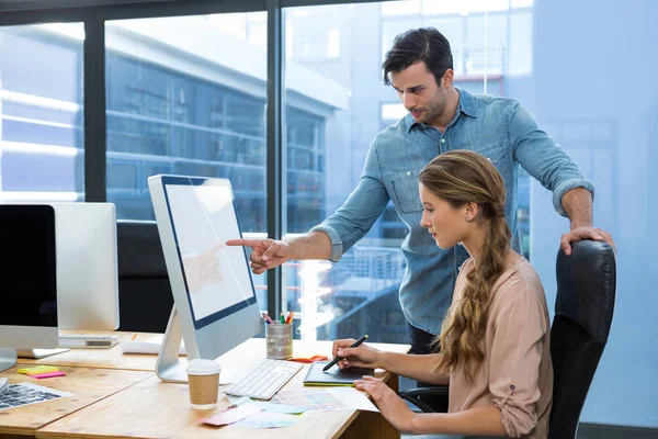 Graphic designer working at desk with colleague — Stock Photo, Image