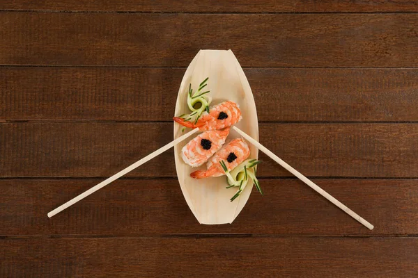 Tres nigiri sushi servidos con palillos en plato de barco de madera — Foto de Stock