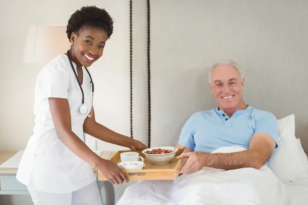 Porträt einer Krankenschwester, die einem älteren Patienten das Frühstück serviert — Stockfoto