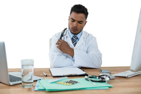Doctor looking medical report at desk — Stock Photo, Image